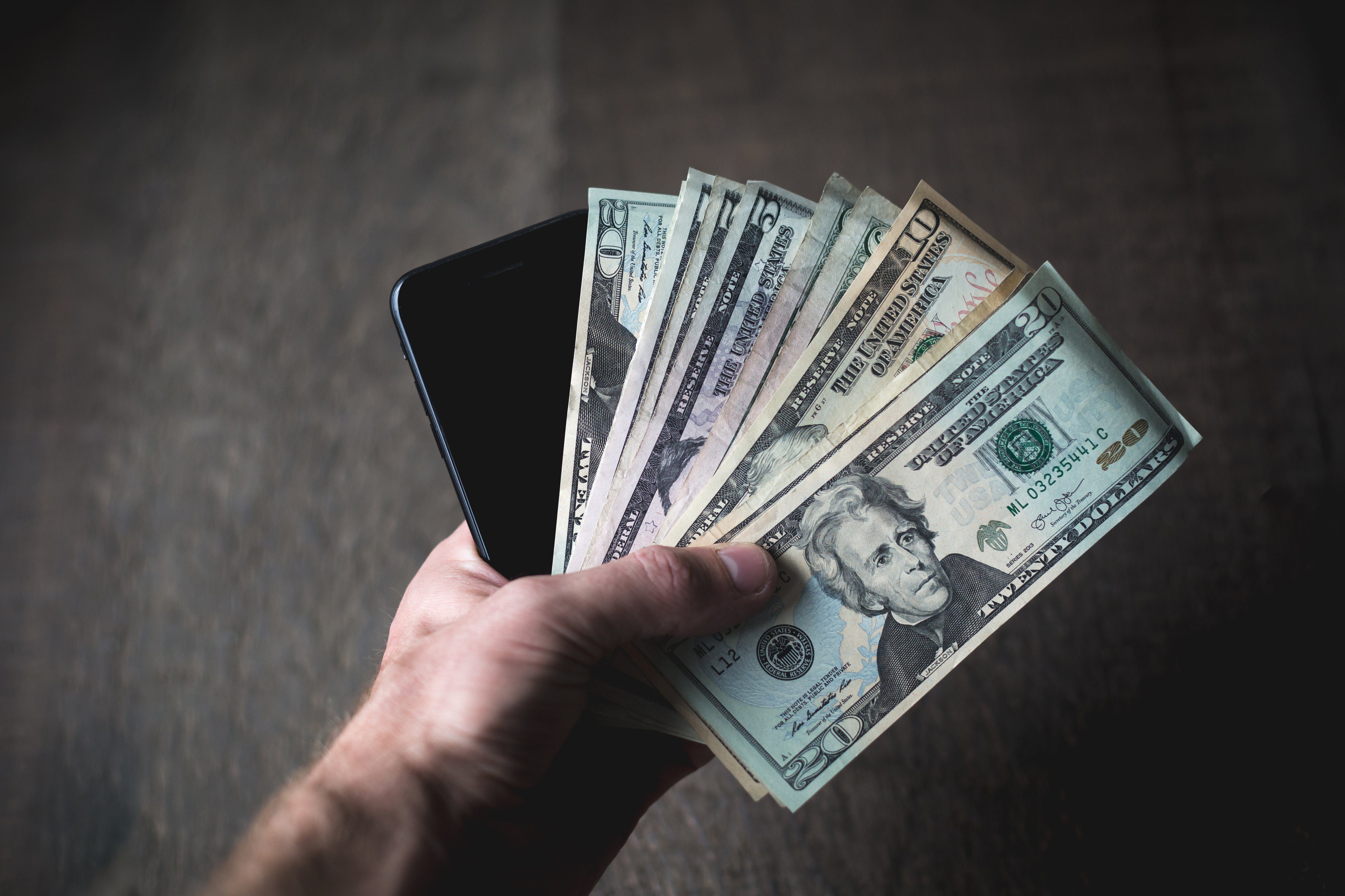 Man with a cell phone and American  dollars in his hand. 