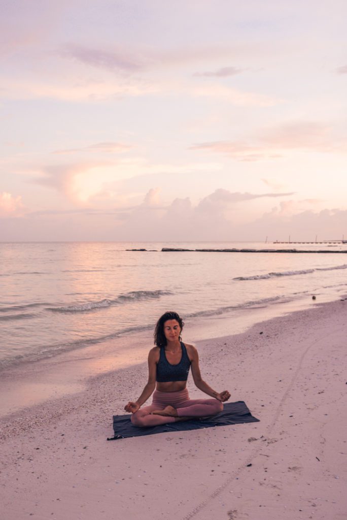 woman meditating on the beach at sunrise