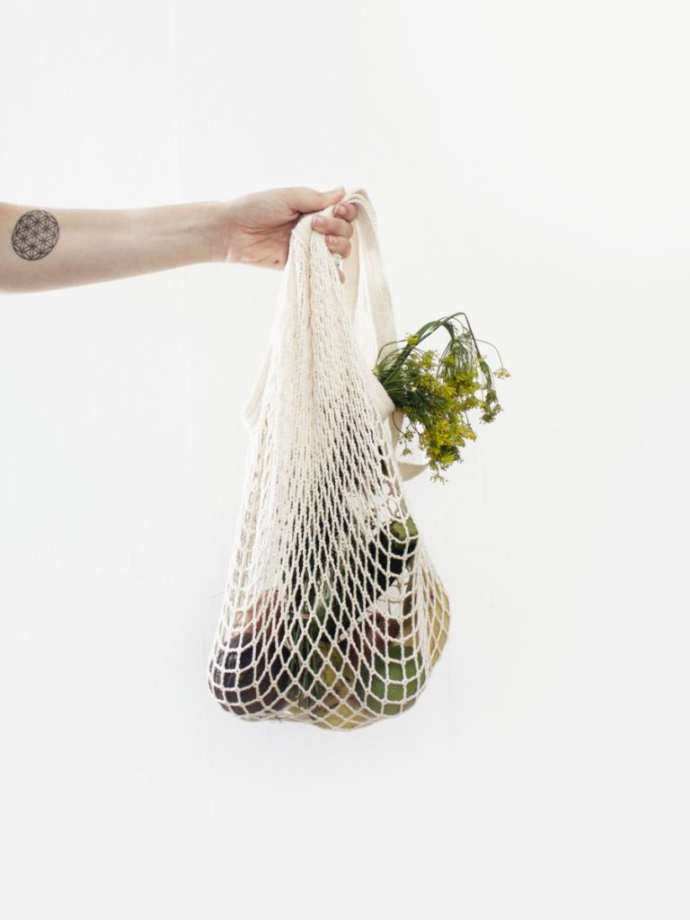 canvas shopping bag with produce inside sustainable travel tips