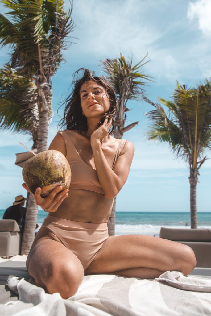 Woman enjoying a coconut on the beach in Tulum