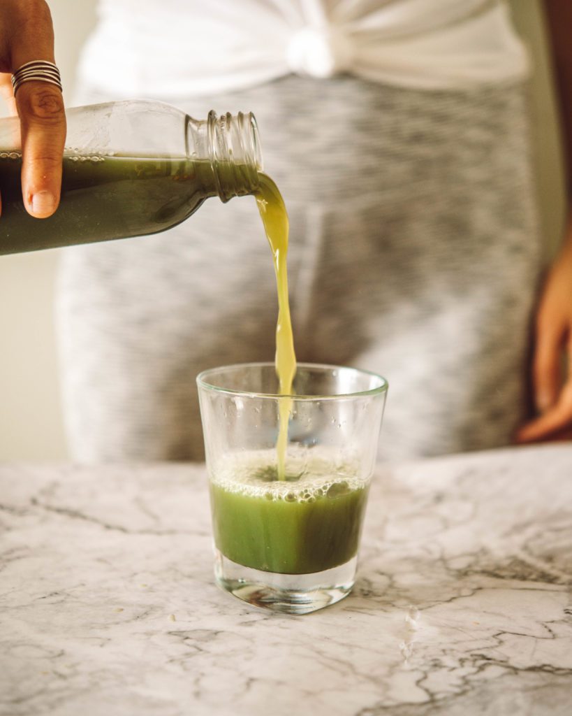 woman pouring green juice into a glass