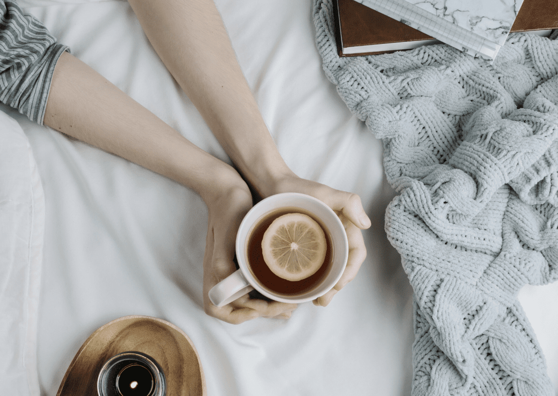 woman holding a mug of tea on the bed