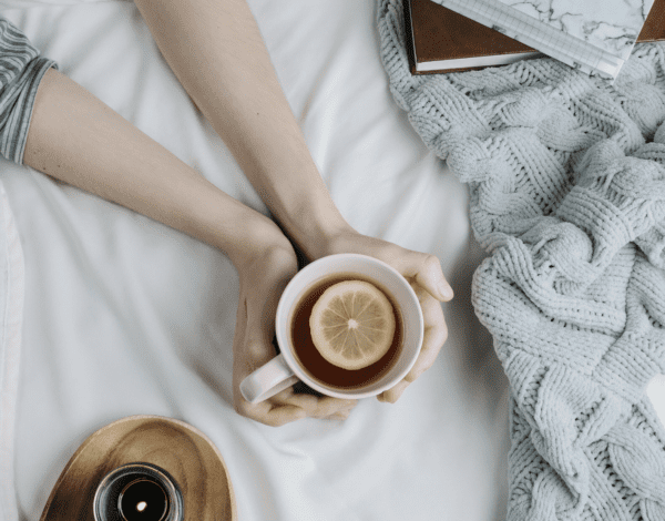 woman holding a mug of tea on the bed