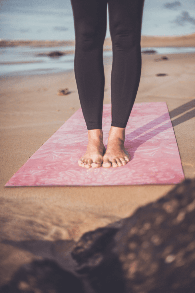 woman standing on a pink yoga mat, portable exercise equipment