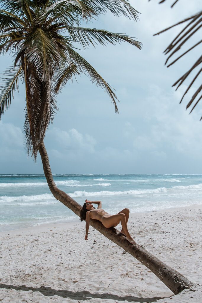 Woman lying on a palm tree in Tulum