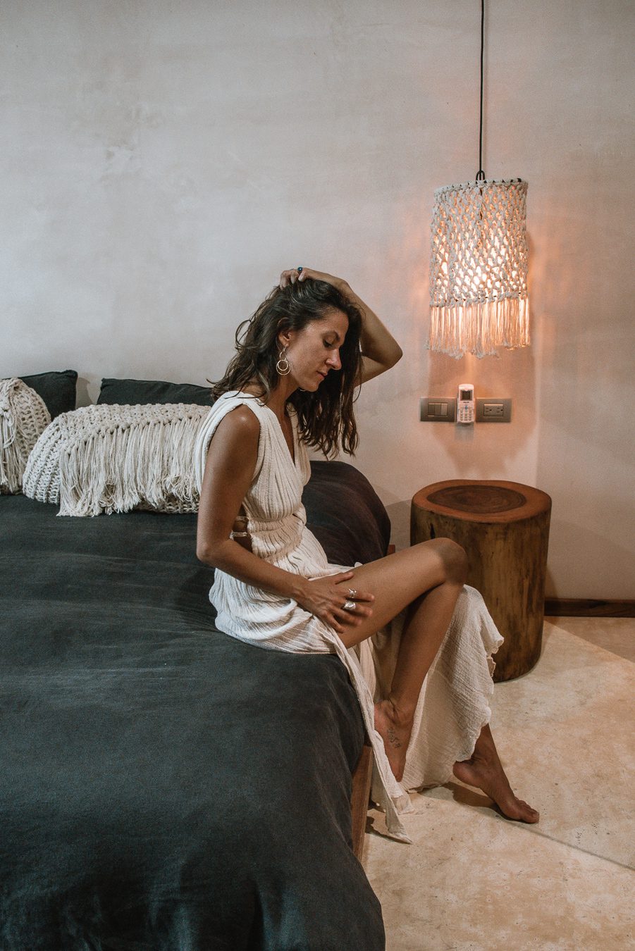 Woman sitting on bed in boutique hotel in Tulum Mexico