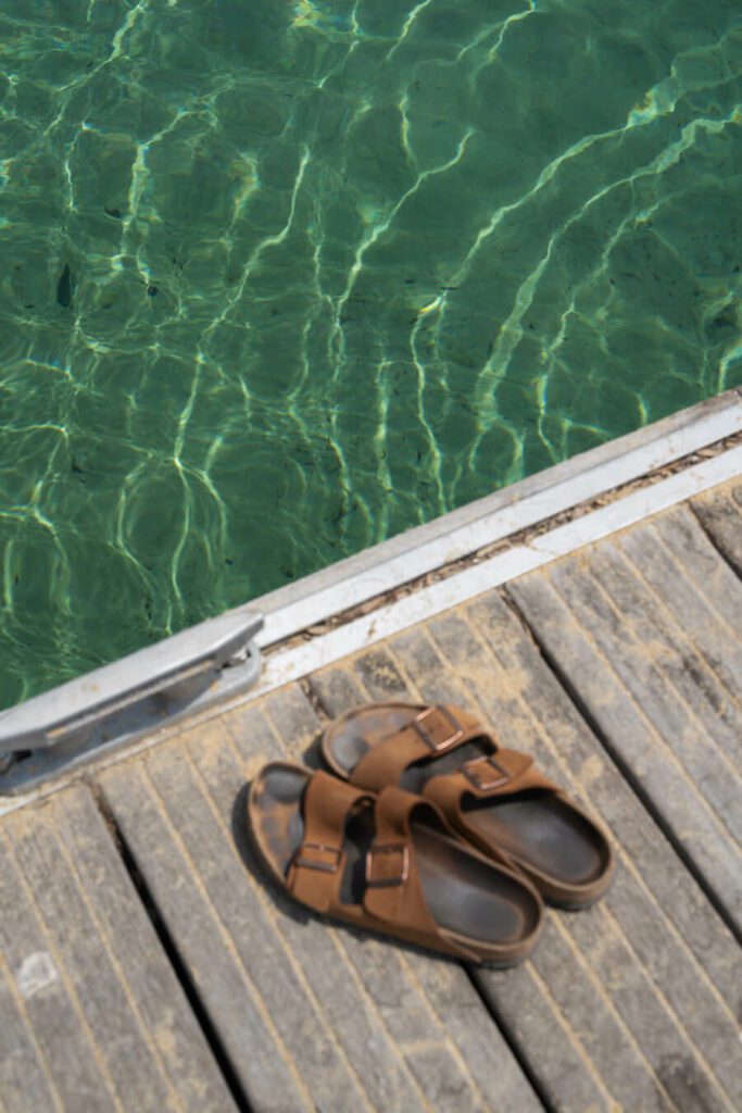 sandals by the emerald green clear water in Greece