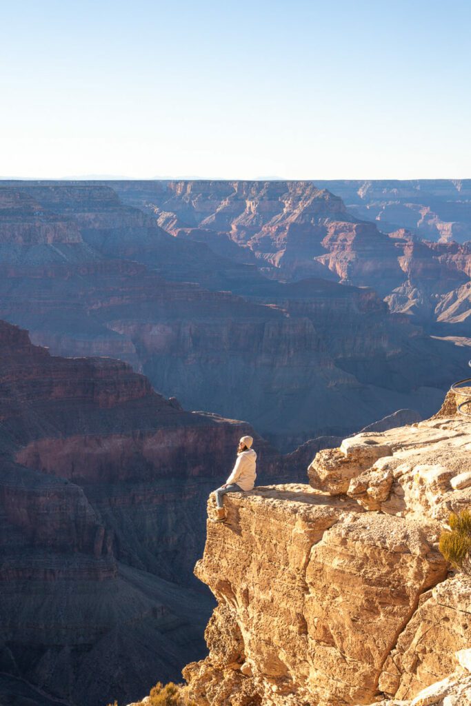 woman sat on the edge of the grand canyon