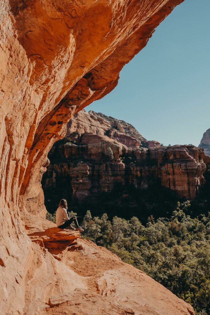 woman sitting on the edge of a Sedona Cave