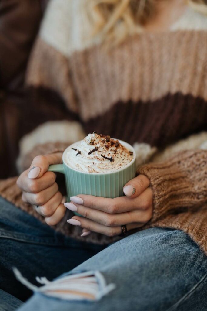 woman cradling a hot chocolate in cafe