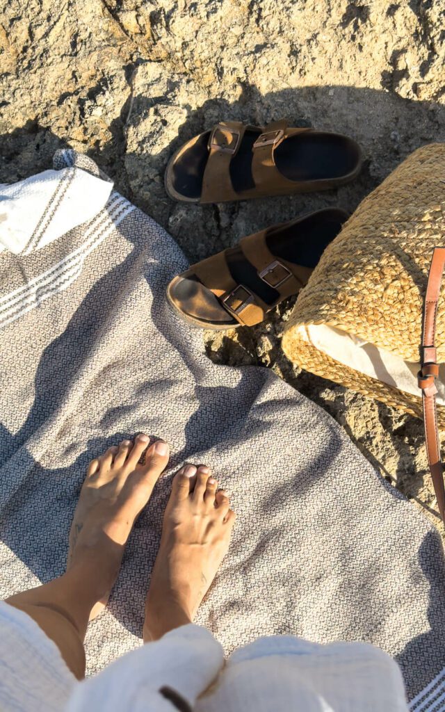 beach towel, bag and sandals on a rocky beach
