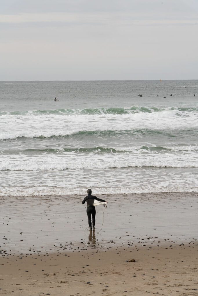 surfer entering the water in Pacific City Oregon, one of the best oregon coast towns