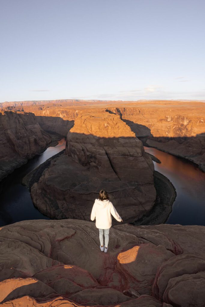 woman watching a sunrise at horseshoe bend