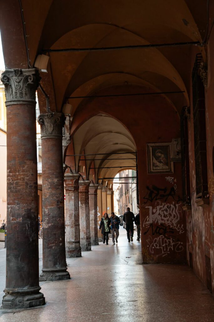 walking through a portico on a Bologna itinerary