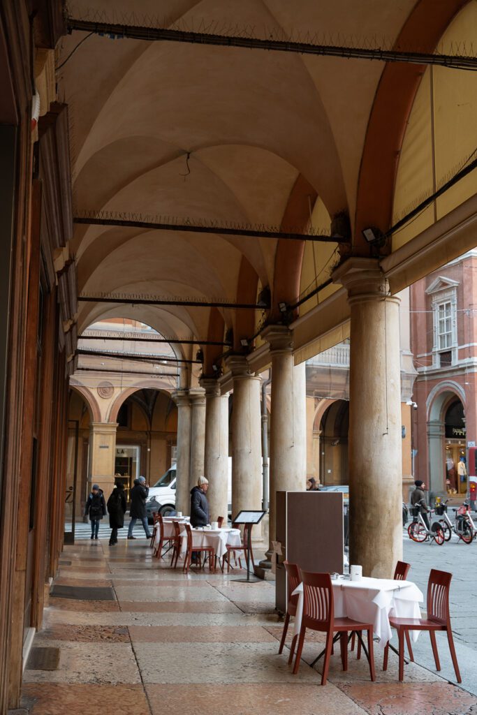 a portico with tables outside in bologna italy