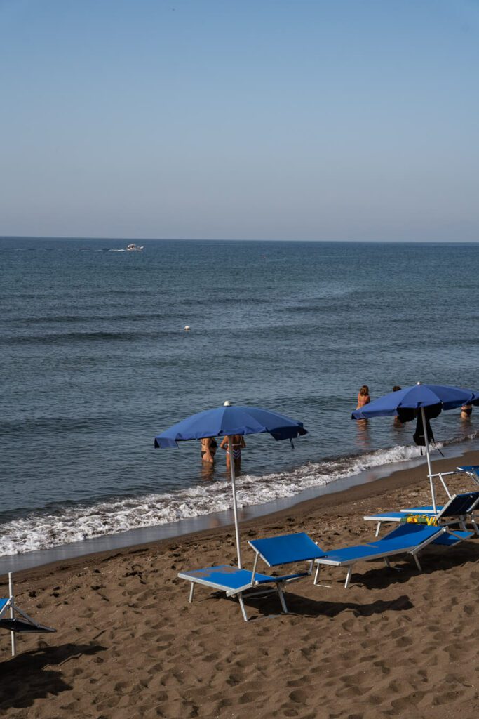 beach in procida with blue parasol and loungers
