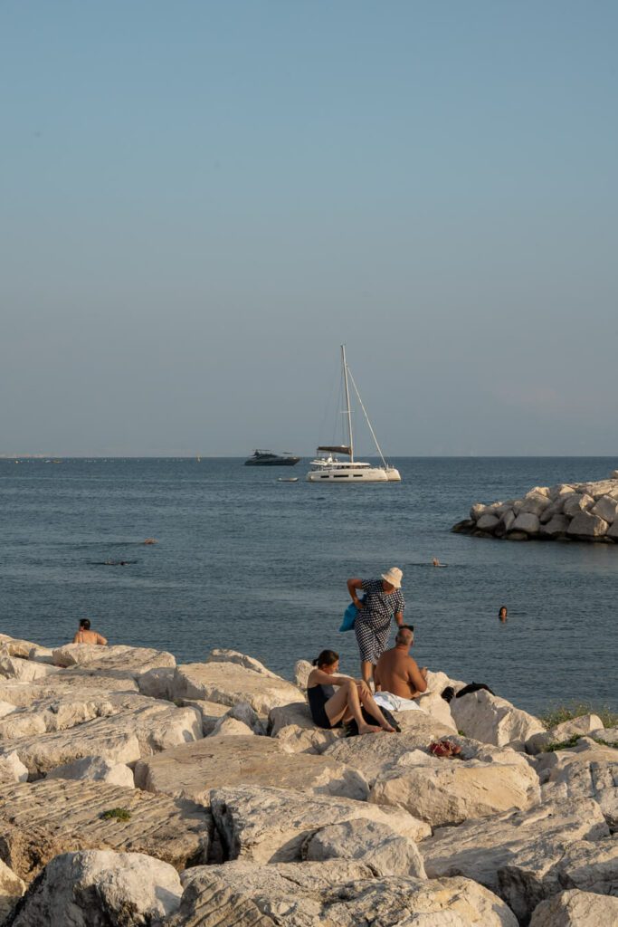 bathers on rocks by the sea in naples italy