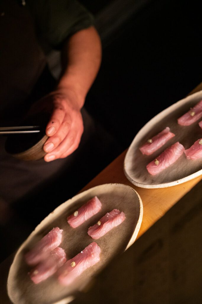 chef plating raw fish at Yapa restaurant milano