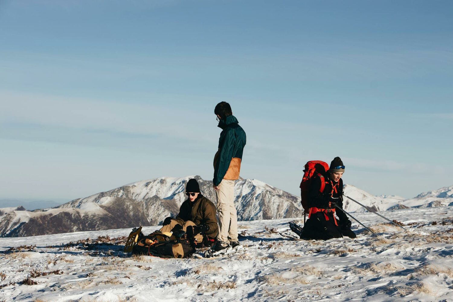 unrecognizable backpackers recreating on snowy terrain during hiking in highlands